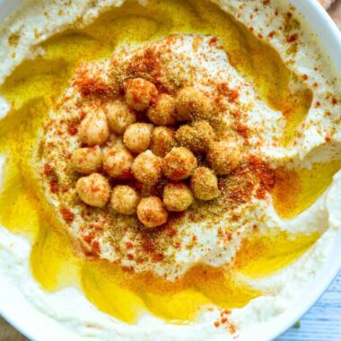 A bowl of hummus with cumin and paprika sprinkled on top