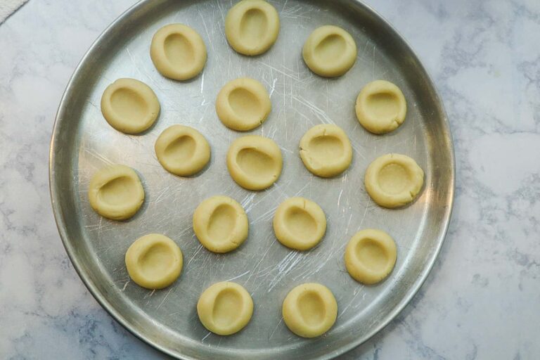 A circular sheet pan filled with thumbprint cookie dough ready to be baked