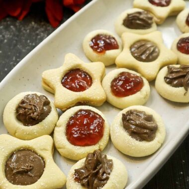 Thumbprint cookies on a plate filled with strawberry jam and Nutella Chocolate