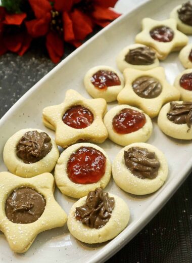 Thumbprint cookies on a plate filled with strawberry jam and Nutella Chocolate