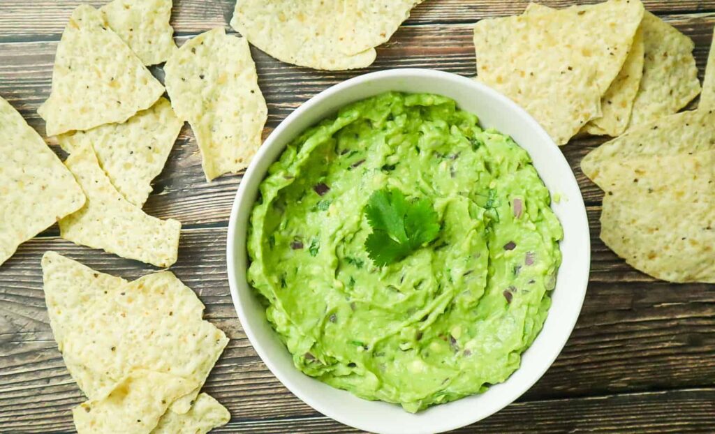 A bowl of best guacamole with a tortilla chips on the side 