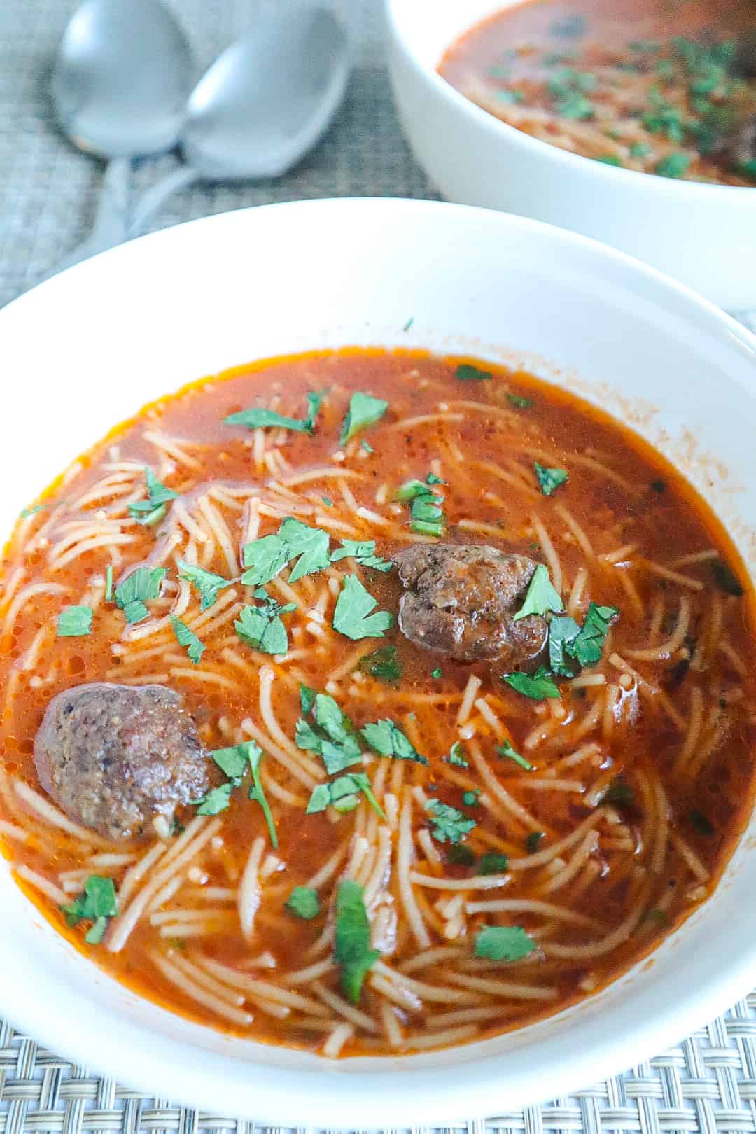 A bowl of vermicelli soup with meatballs and parsley