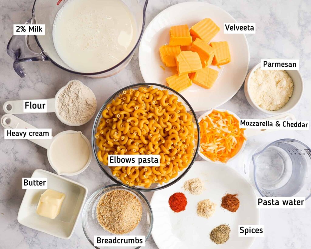 A bowl of pasta, cheddar, mozzarella, parmesan, velveeta cheese, milk, water, spices, heavy cream, flour and butter 