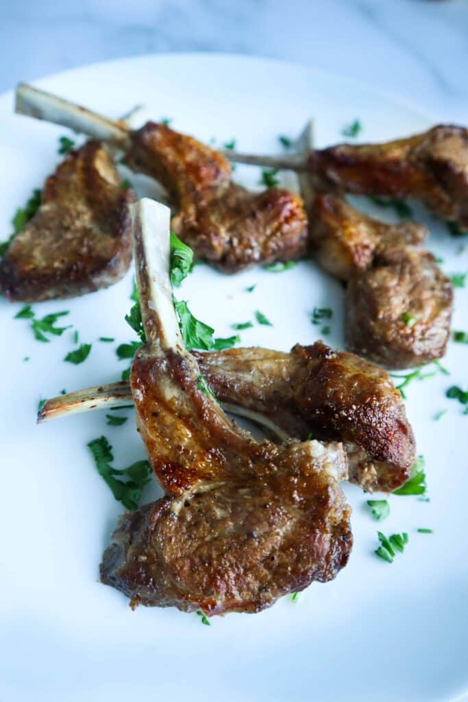 A plate of baked lamb chops with chopped parsley as a garnish