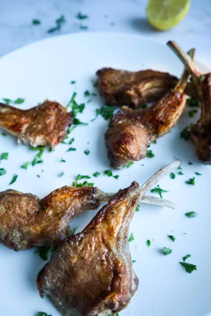 A plate of  lamb chops with chopped parsley as a garnish