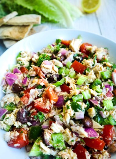 A bowl of mediterranean tuna salad and slices of pita bread on the side.