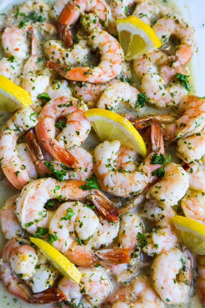 Baked shrimp in an oven tray with parsley and lemon slices