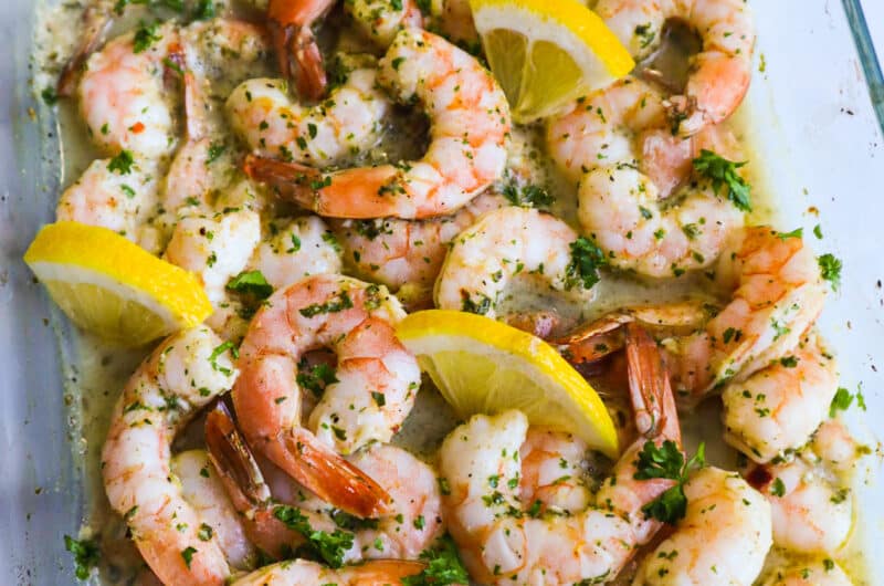 Baked shrimp in an oven tray with parsley and lemon slices