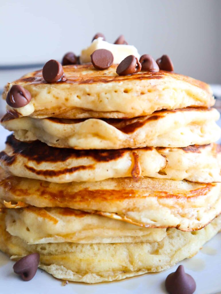 layers of chocolate chip pancakes with butter, more chocolate chip and maple syrup