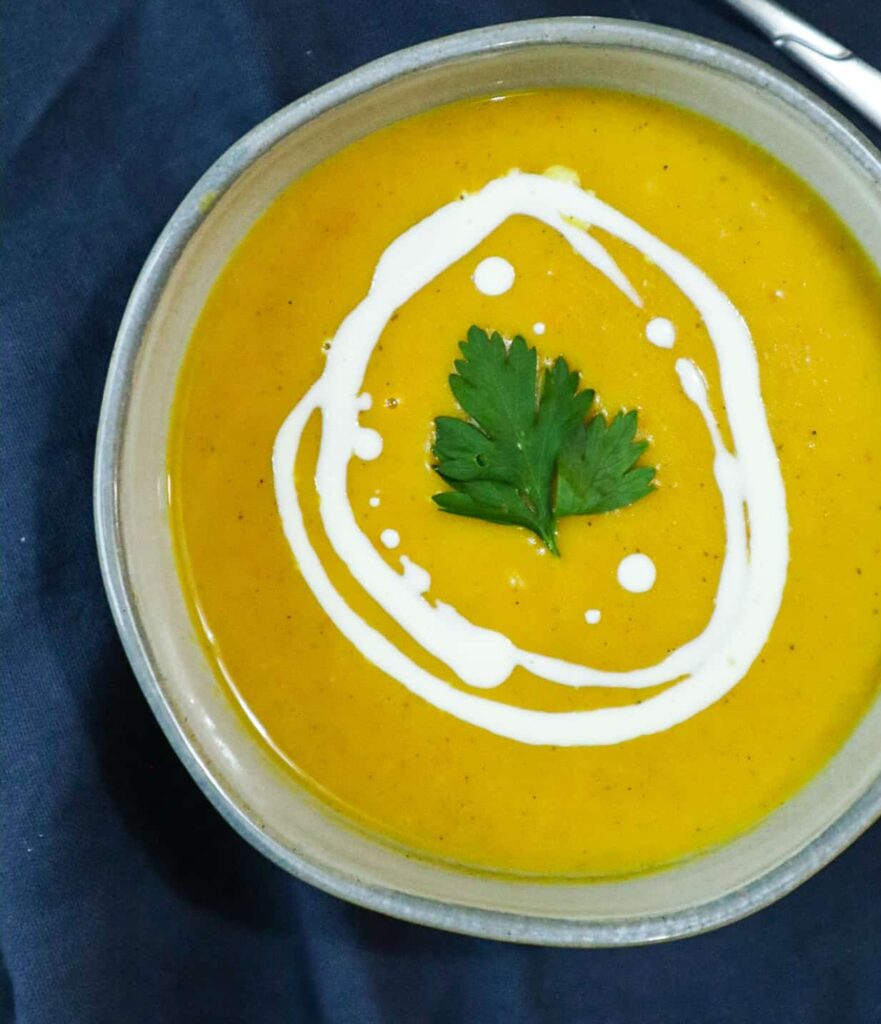 A bowl of pumpkin soup with parsley as a garnish