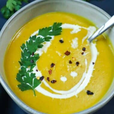 A bowl of pumpkin soup with parsley as a garnish