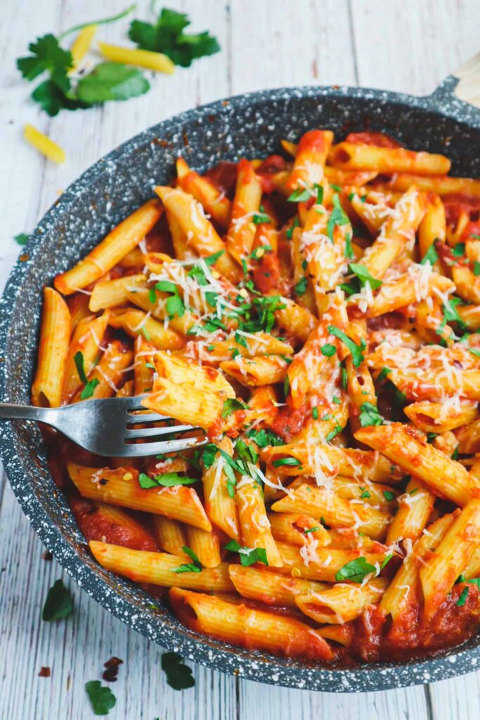 A pan pf spicy penne arabbiata with parmesan and parsley on top
