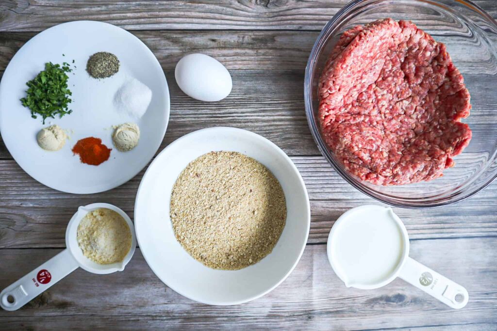 A bowl of ground beef, breadcrumbs, milk, spices, parmesan cheese and egg. 