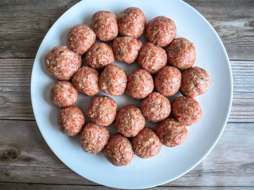 A plate of shaped raw meatballs before cooking