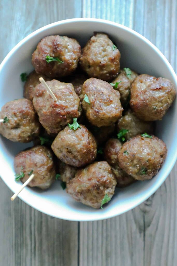 A bowl of meatballs with chopped parsley as garnish