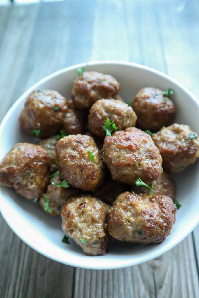 A bowl of meatballs with chopped parsley as garnish
