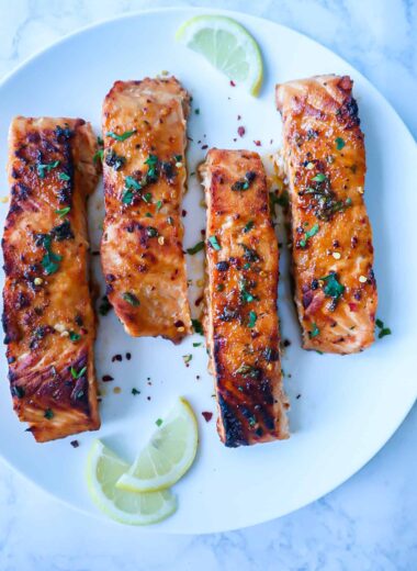 A dish of salmon with sprinkles of parsley and chili flakes.