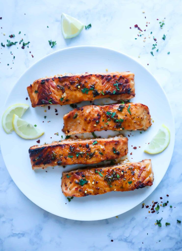 A dish of air fryer salmon with sprinkles of parsley and chili flakes.