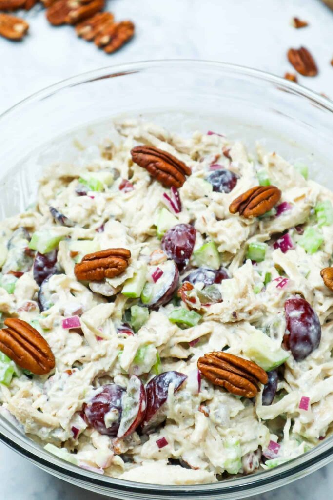 A bowl of chicken salad with pecans on top and sides