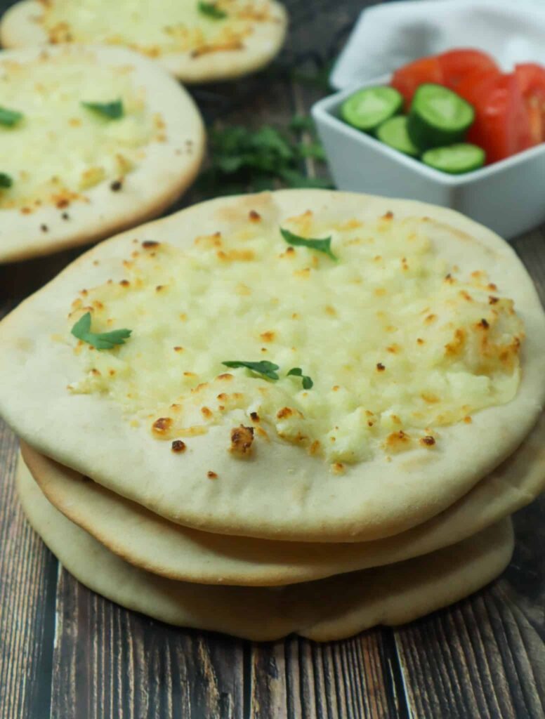 A cheese flatbread, a bowl of cucumbers and tomatoes and more manakish