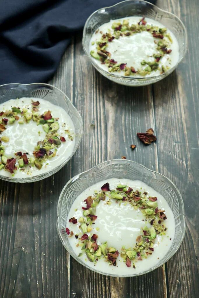 A bowl of Muhallebi topped with ground pistachios and rose petals