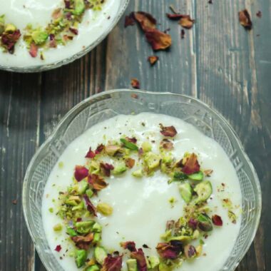 A bowl of Mahalabia topped with ground pistachios and rose petals