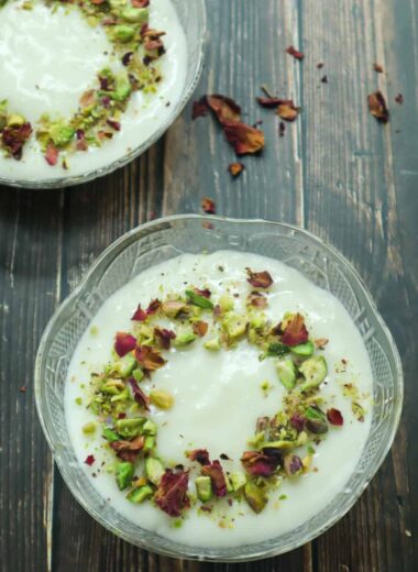 A bowl of Mahalabia topped with ground pistachios and rose petals