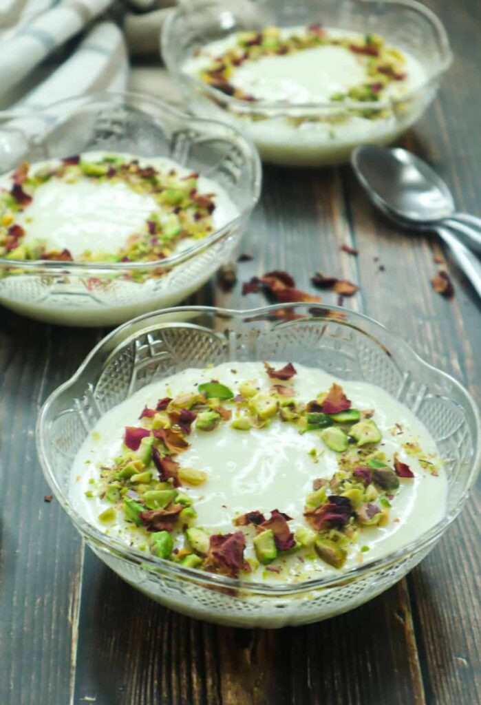 A bowl of Muhallebi topped with ground pistachios and rose petals