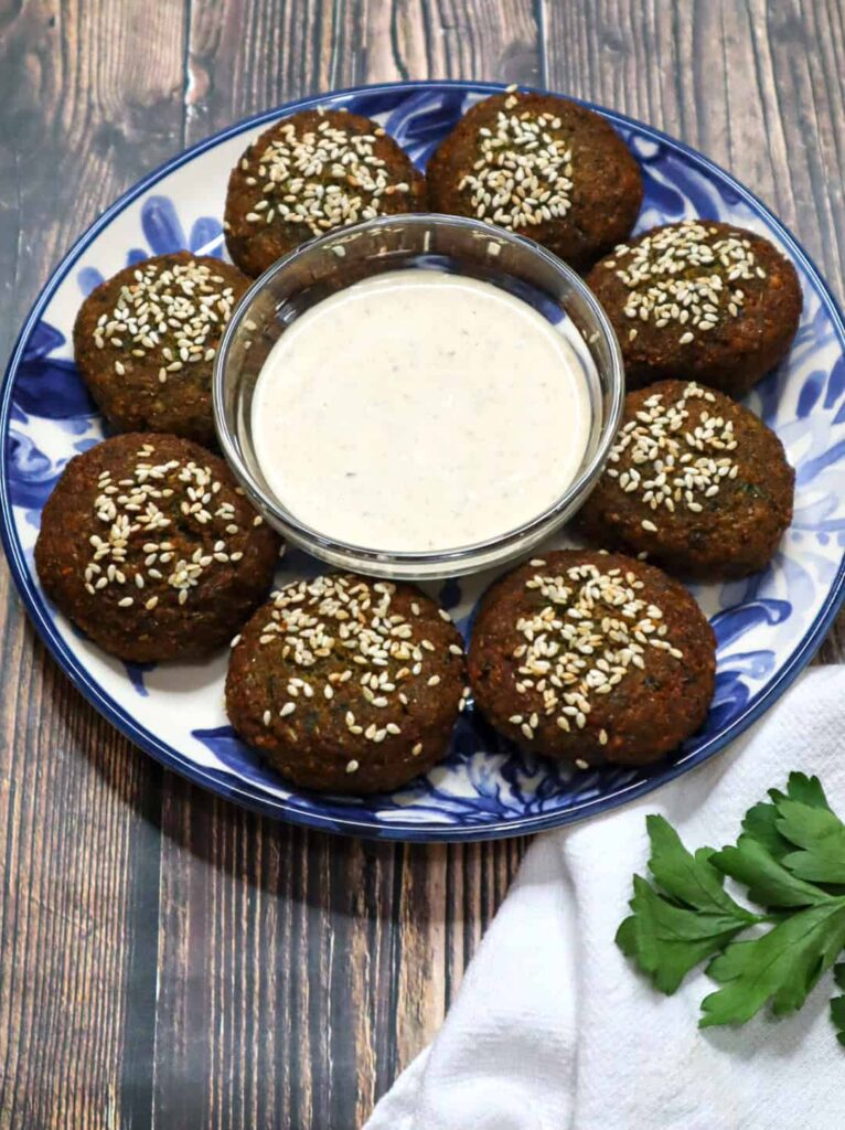 A plate of 8 pieces of Egyptian falafel with a bowl of tahini sauce in the middle