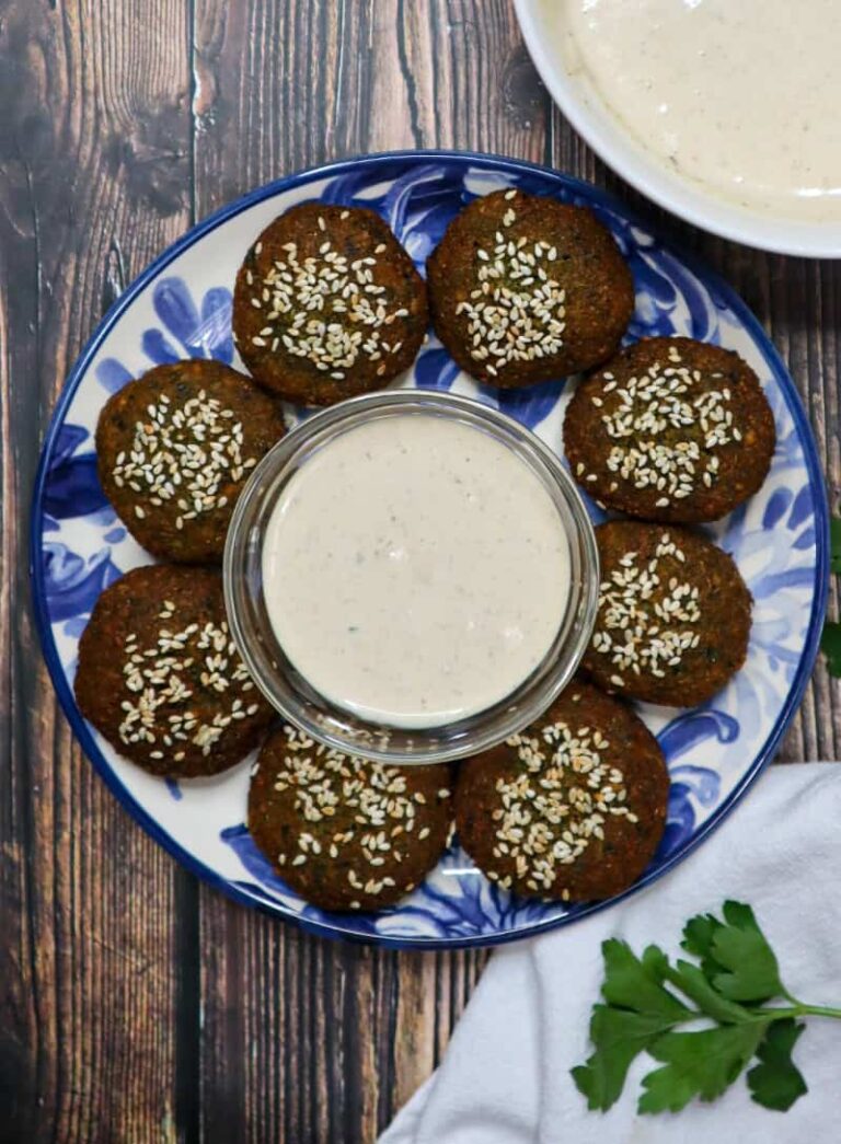 A plate of 8 pieces of falafel with a bowl of tahini sauce in the middle