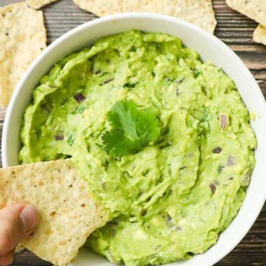 A bowl of guac with tortilla chips
