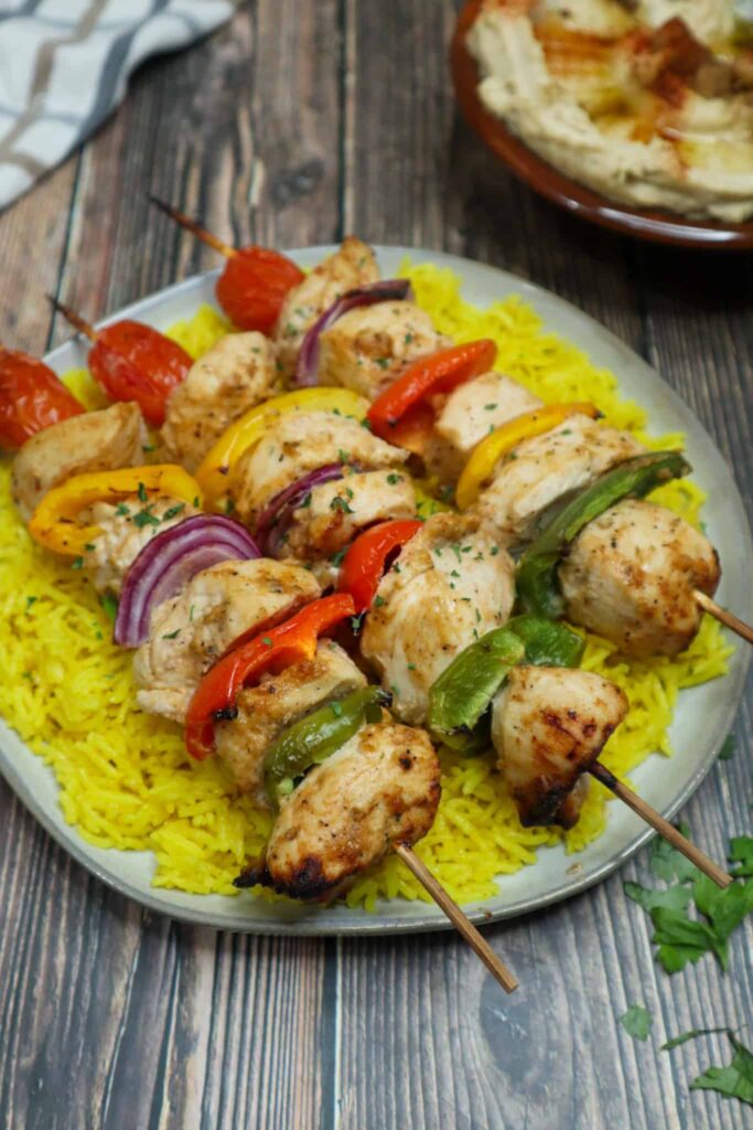 A plate of yellow rice and baked chicken kebabs