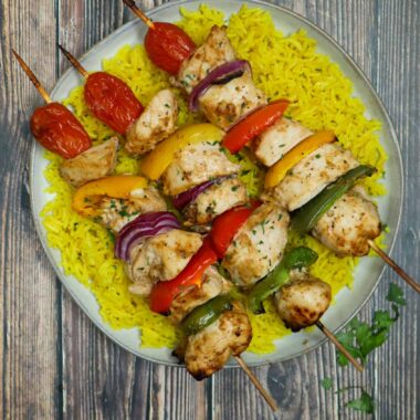 A plate of yellow rice and baked shish kebabs