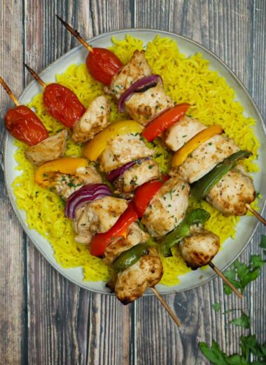 A plate of yellow rice and baked shish kebabs