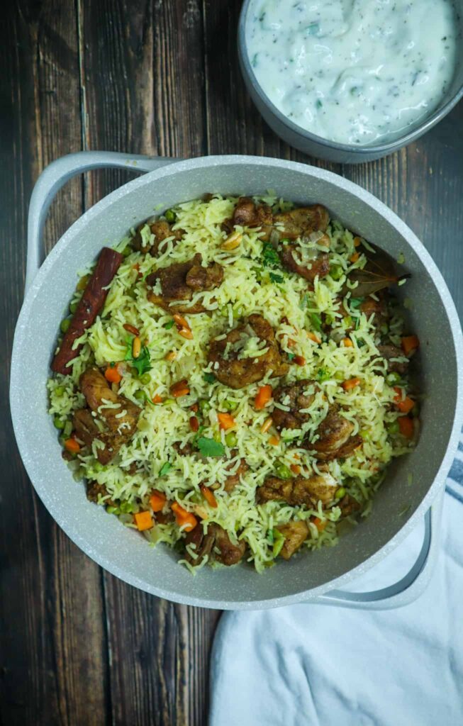 A pot of rice, peas, carrots, thighs, parsley and pine nuts