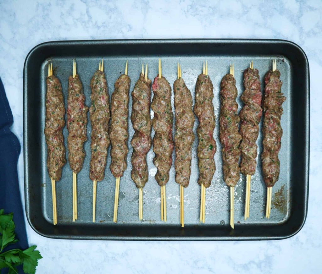 A tray of kofta kebab in skewers before baking