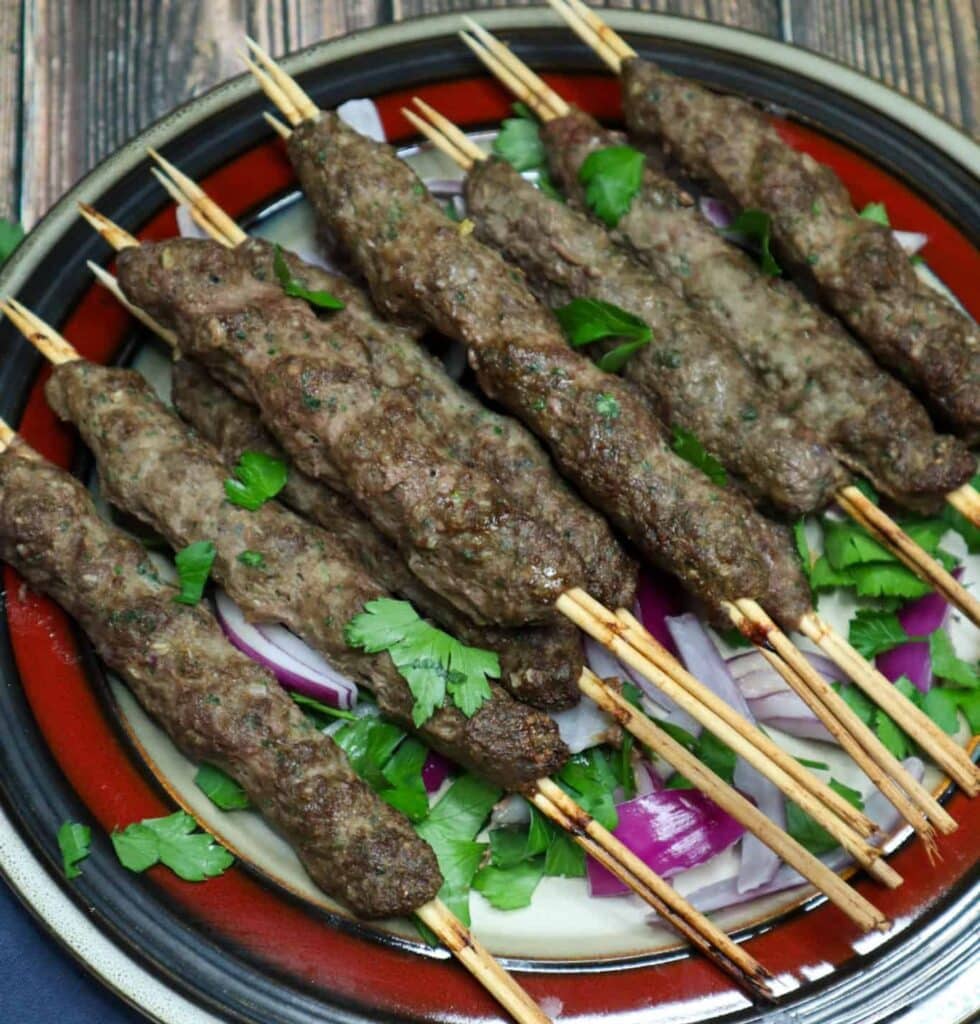 A dish of beef kofta kebab with tahini sauce on the side