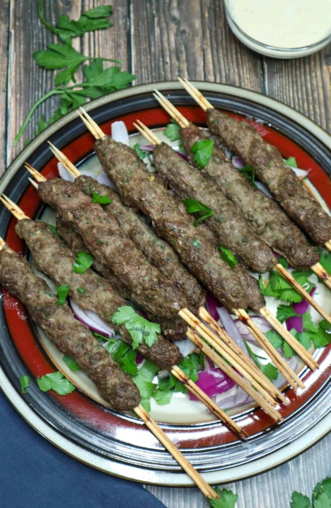 A dish of kebabs with tahini sauce on the side