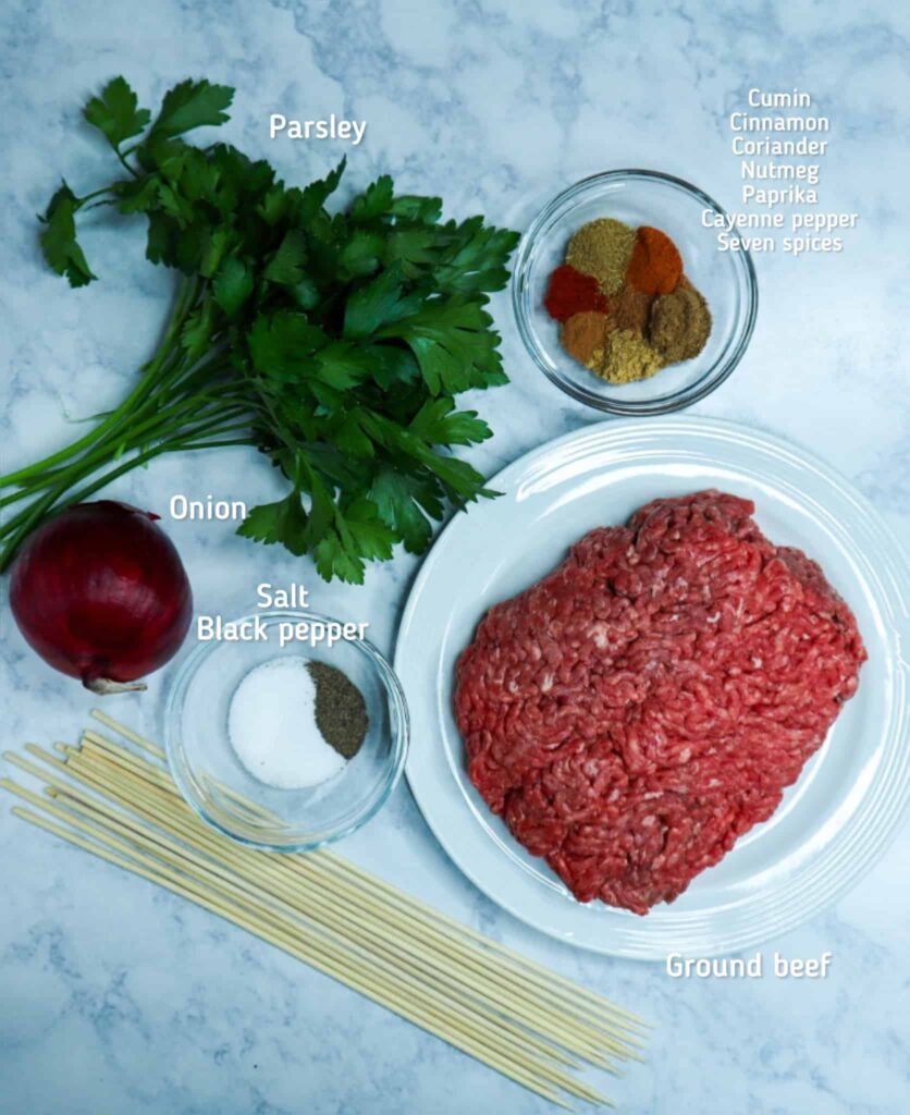 A dish of ground beef, parsley, onion, spices and wooden sticks
